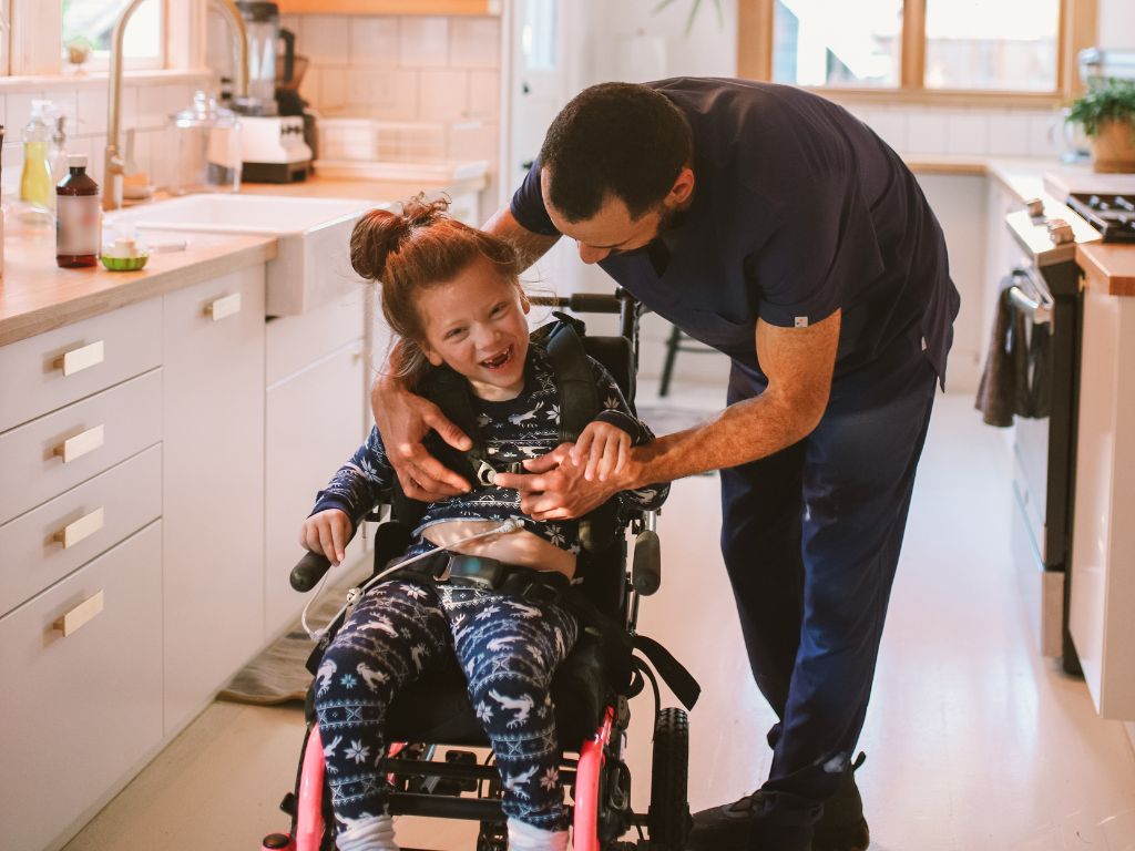Girl in wheelchair being helped by an aide