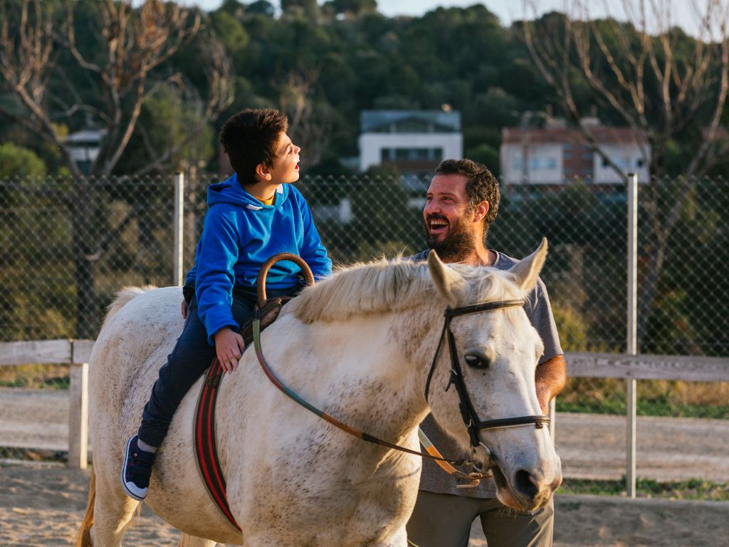 child riding horse supervised by adult