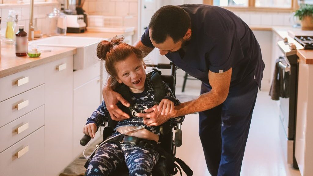 Girl in wheelchair being helped by an aide