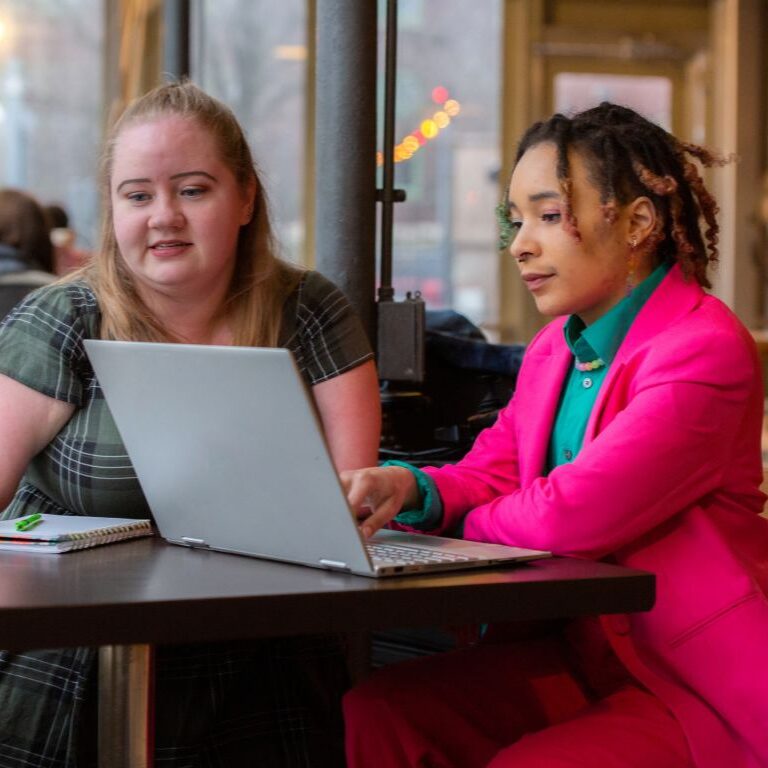 stock photo of two people using a laptop computer at a cafe