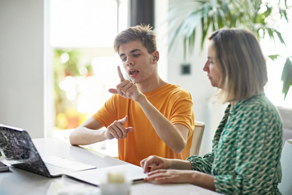 Two people in front of computer communicating with sign language